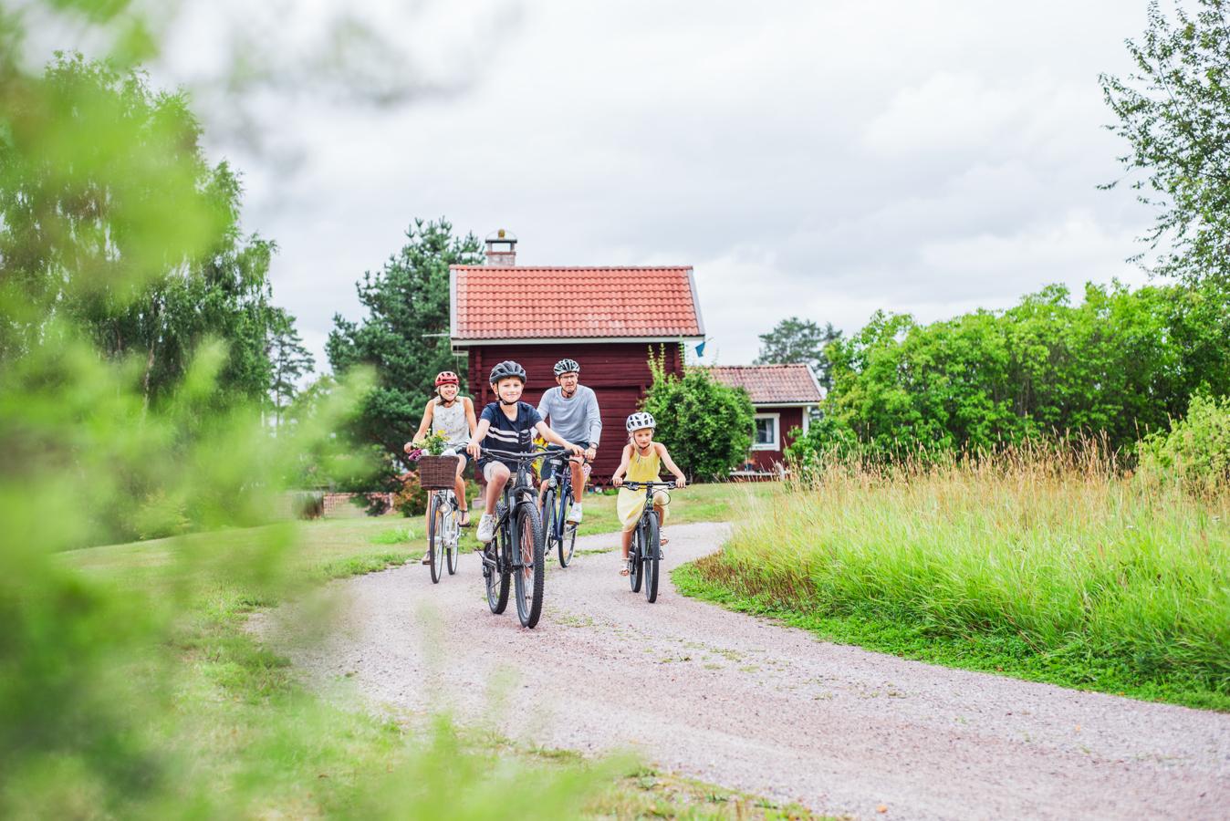 Familj cyklar på grusväg i Dalarna