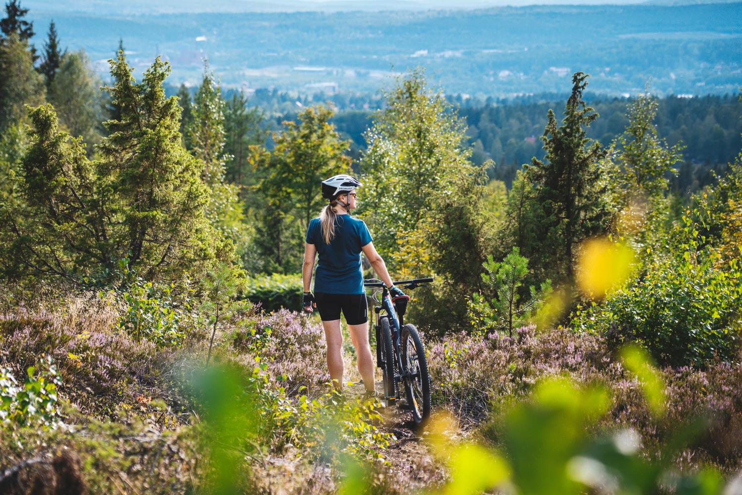En tjej som står vid sin mountain bike i skogen.