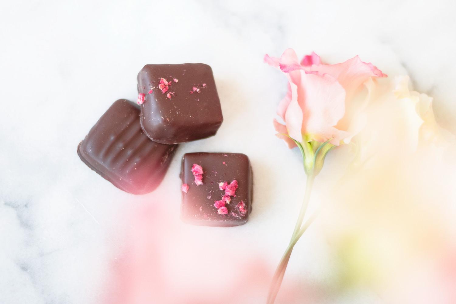 Chokladpraliner med en ros på ett bord.