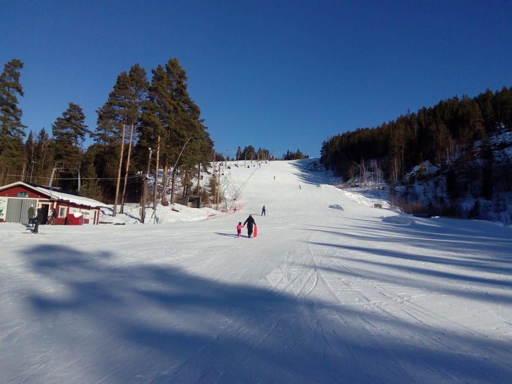 En av nedfarterna där några personer åker skidor i solskenet.