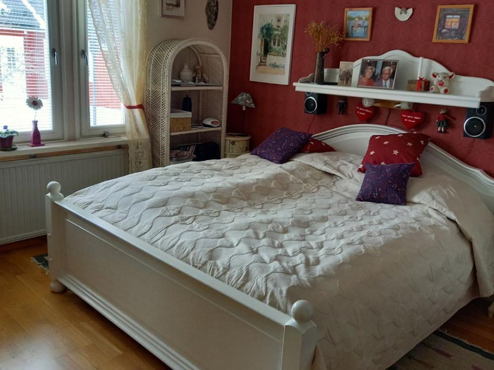 Double bed in white bed frame and with white bedspread.